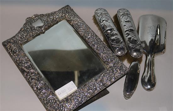 An Edwardian repousse silver mounted photograph frame, Birmingham, 1907, two brushes, a mirror and a toilet jar.